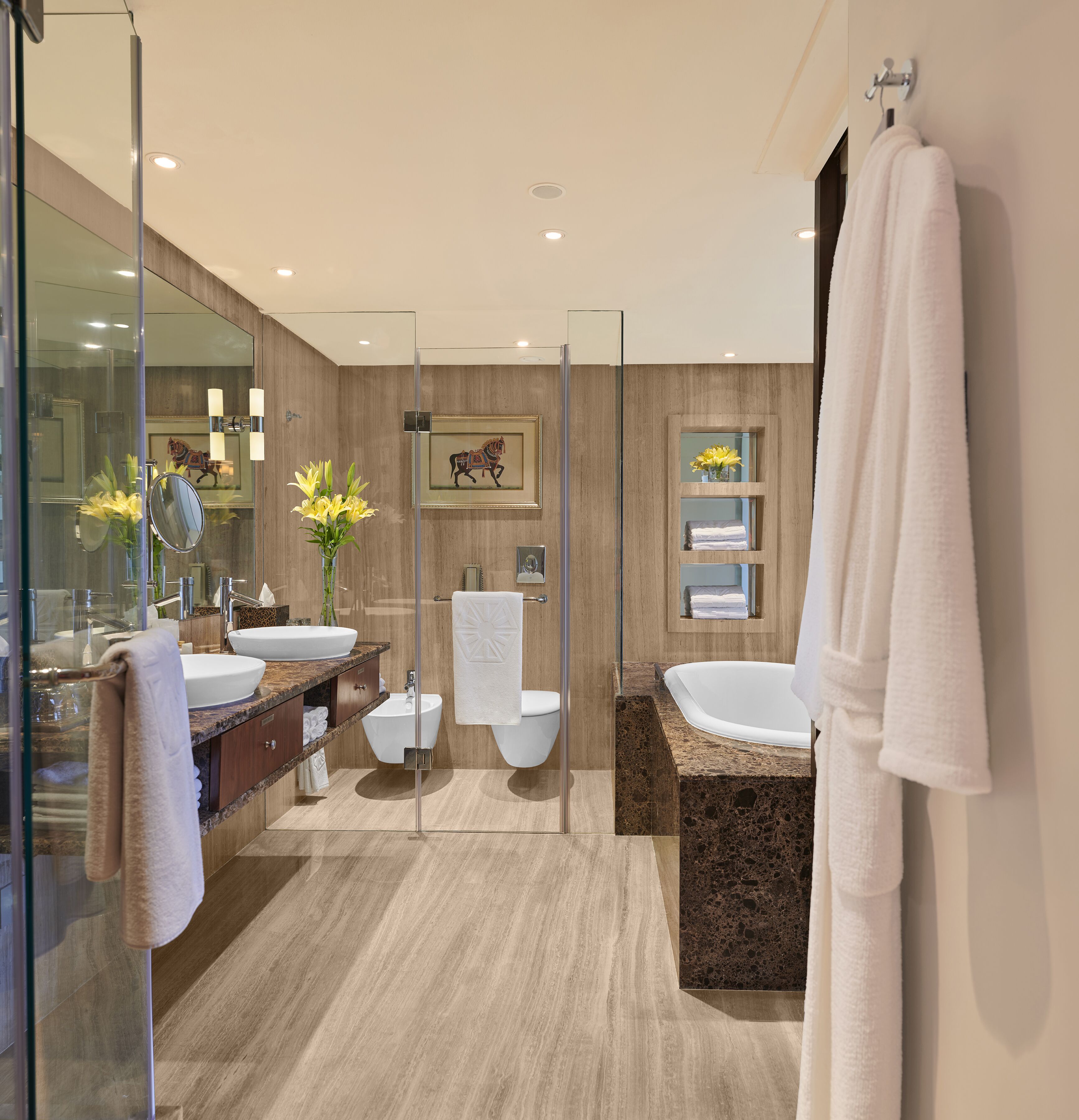 A modern bathroom with a glass shower enclosure, two sinks, a bidet, and a bathtub.