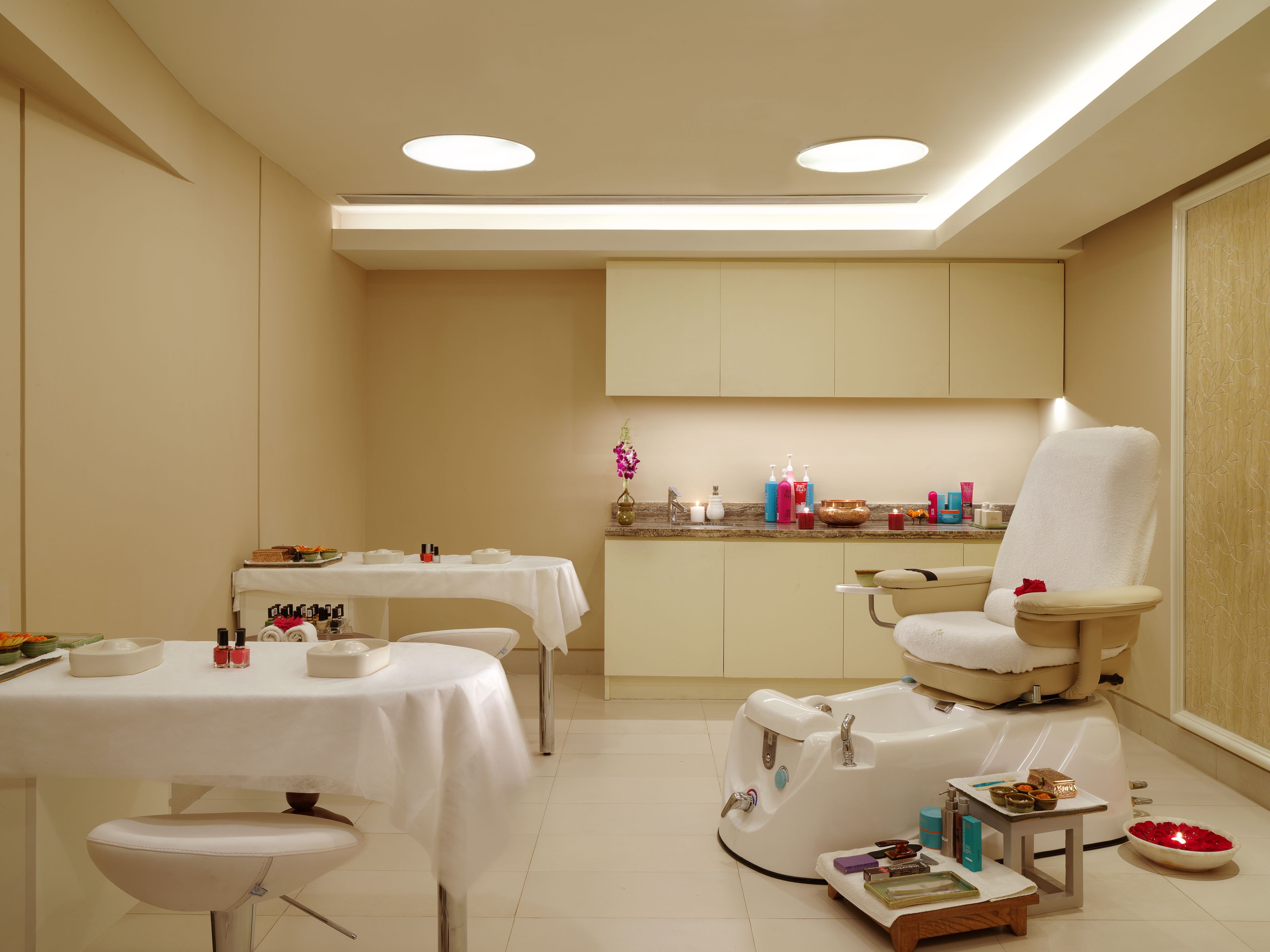 Un cuarto de spa con una camilla de masaje, una mesita con artículos de tocador y un lavabo.