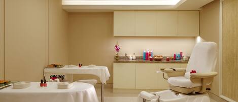 Un cuarto de spa con una camilla de masaje, una mesita con artículos de tocador y un lavabo.