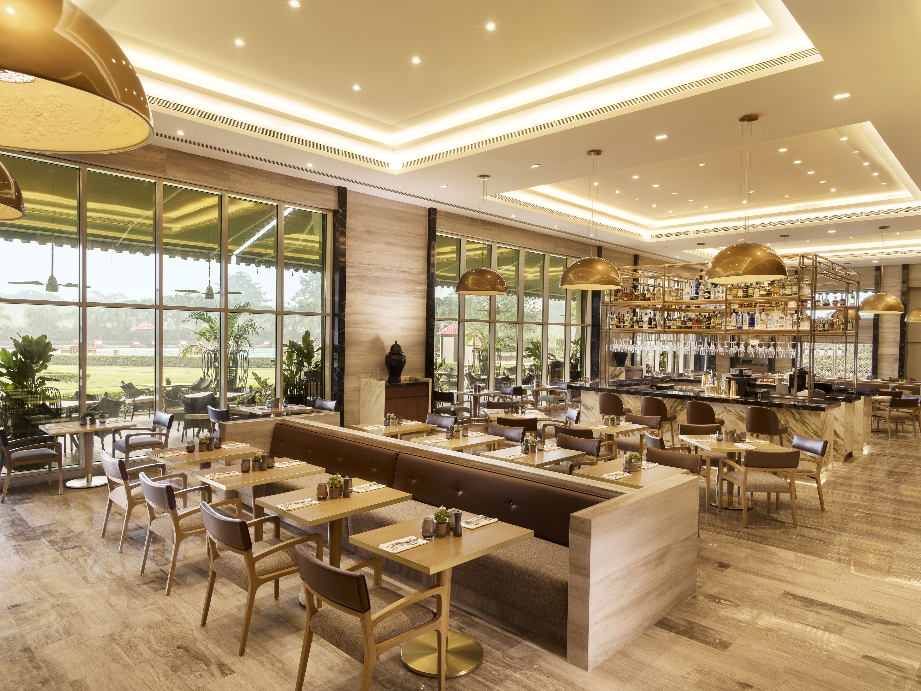 A spacious restaurant with a bar area, large windows offering a view of the outdoors, and a variety of seating options including tables and booths.