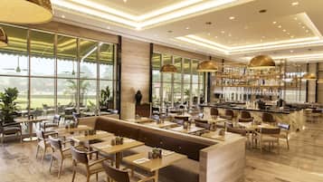 A spacious restaurant with a bar area, large windows offering a view of the outdoors, and a variety of seating options including tables and booths.