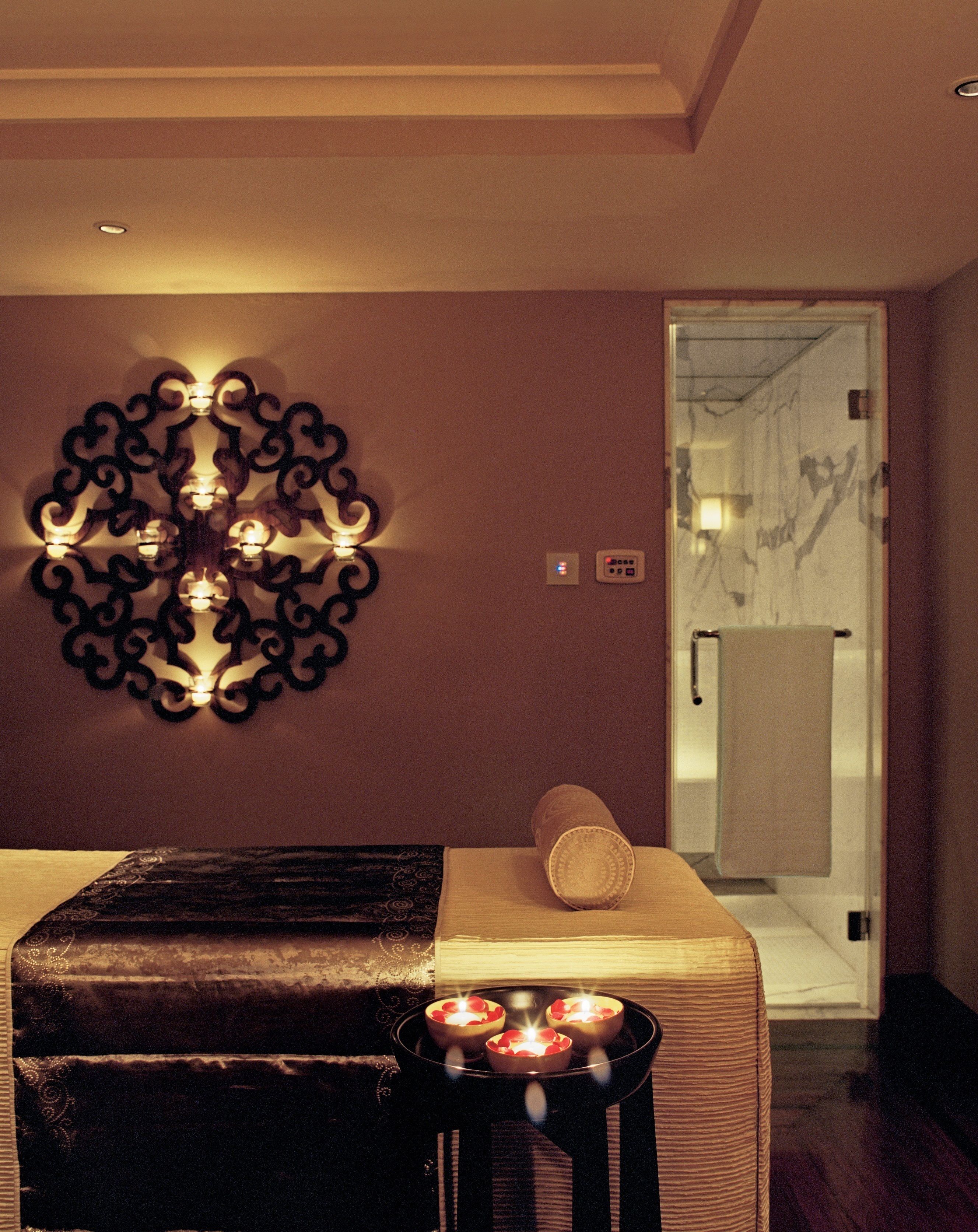 A room with a bed, a wall-mounted light fixture, and a small table with candles.
