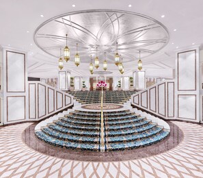 A grand staircase with a circular design, marble walls, and a chandelier.