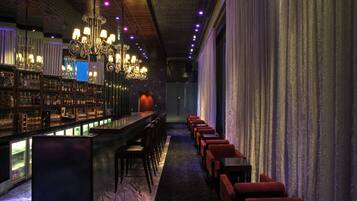 Una zona de bar con una barra larga, varias sillas y un candelabro.