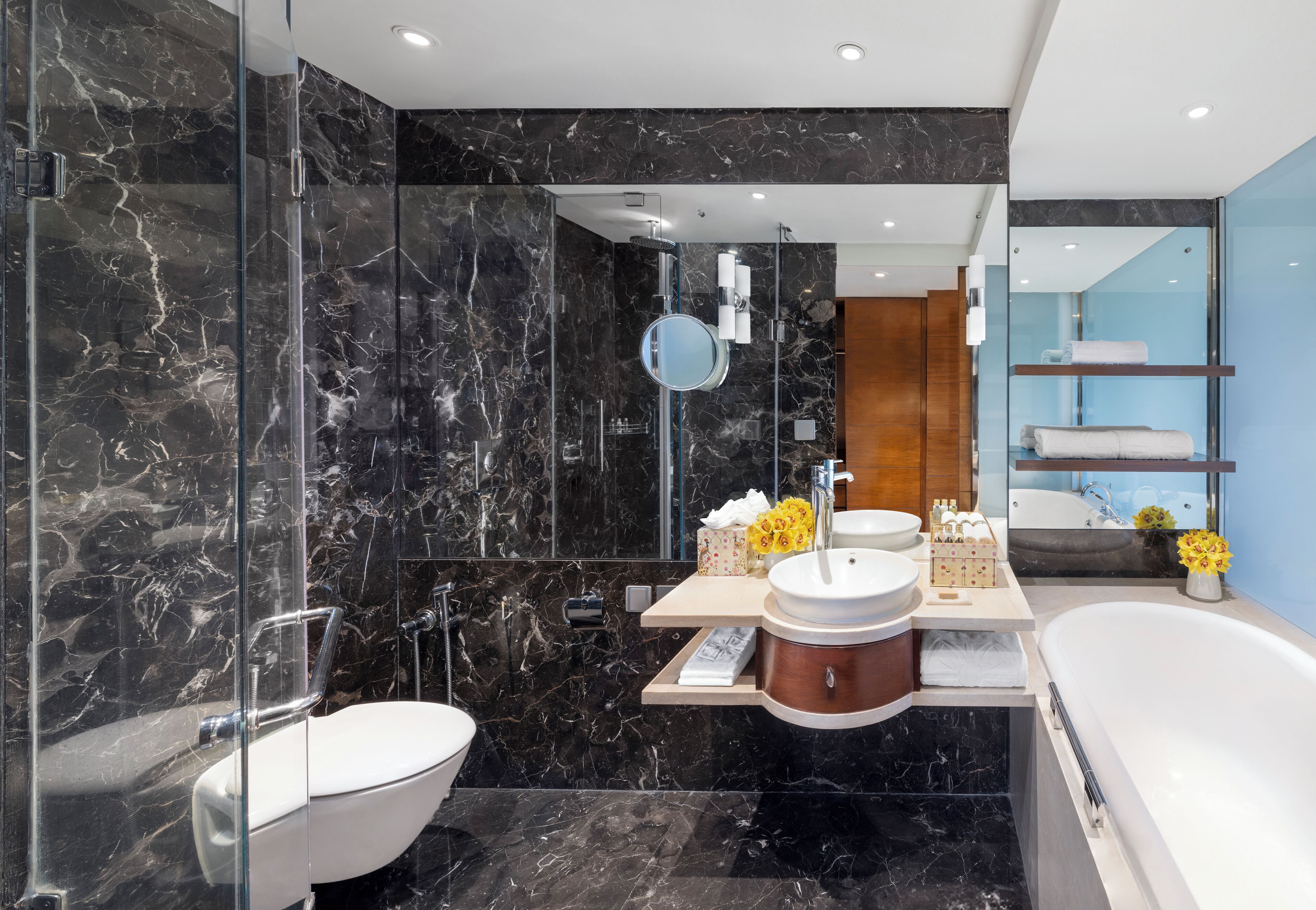 Un baño moderno con pared de mármol, una bañera independiente, un tocador doble y un espejo grande.