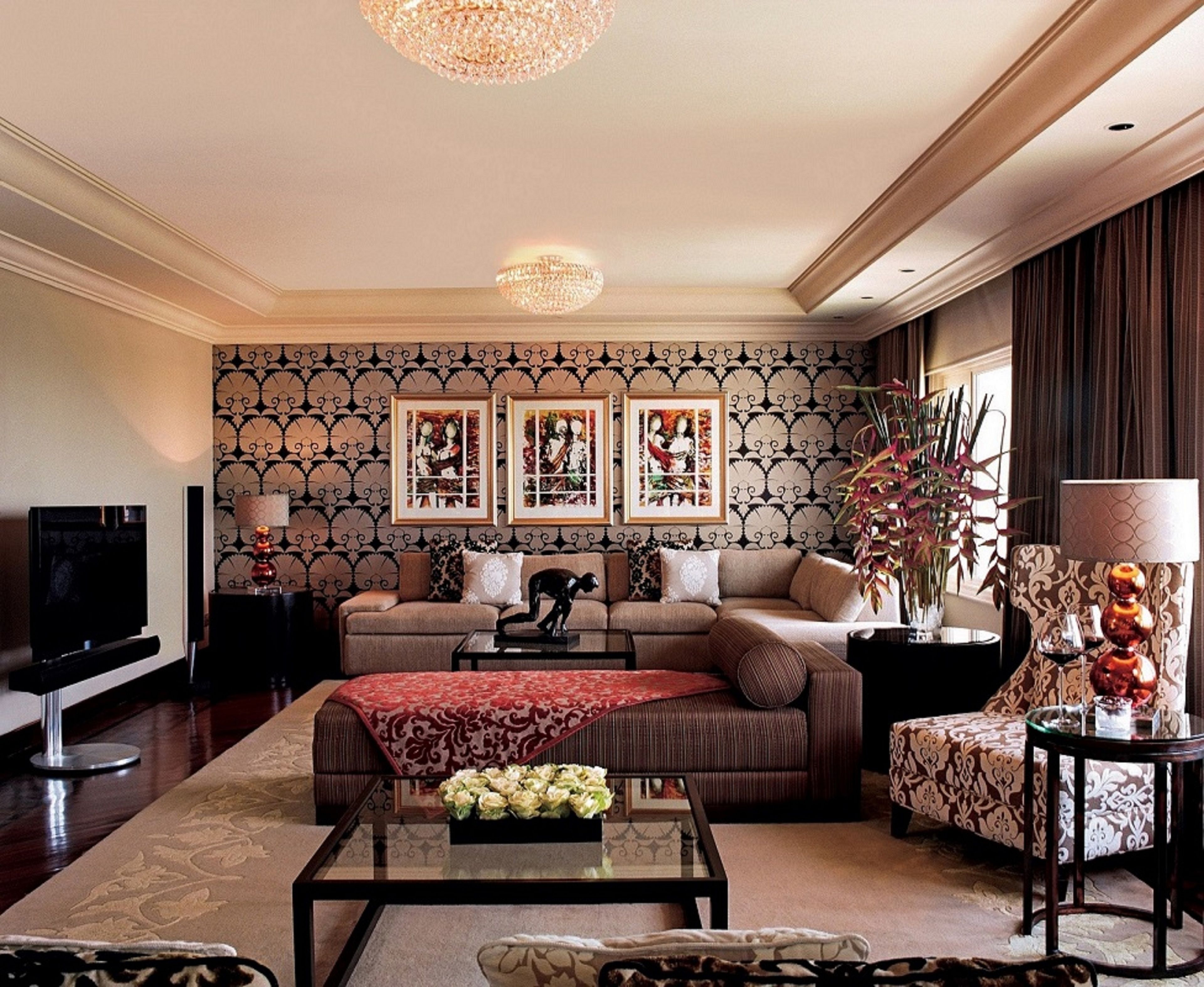 A living room with a sofa, a coffee table, a TV, framed pictures on the wall, and a decorative plant.