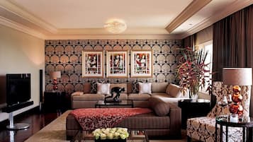 A living room with a sofa, a coffee table, a TV, framed pictures on the wall, and a decorative plant.
