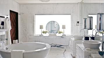 A modern bathroom with a freestanding bathtub, two sinks, and a large window providing natural light.