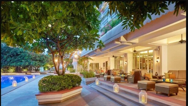 A hotel lobby with a pool, outdoor seating, and a staircase leading to the upper floors.