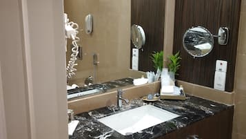 Un baño moderno con lavamanos de mármol, un espejo grande y un perchero para toallas.