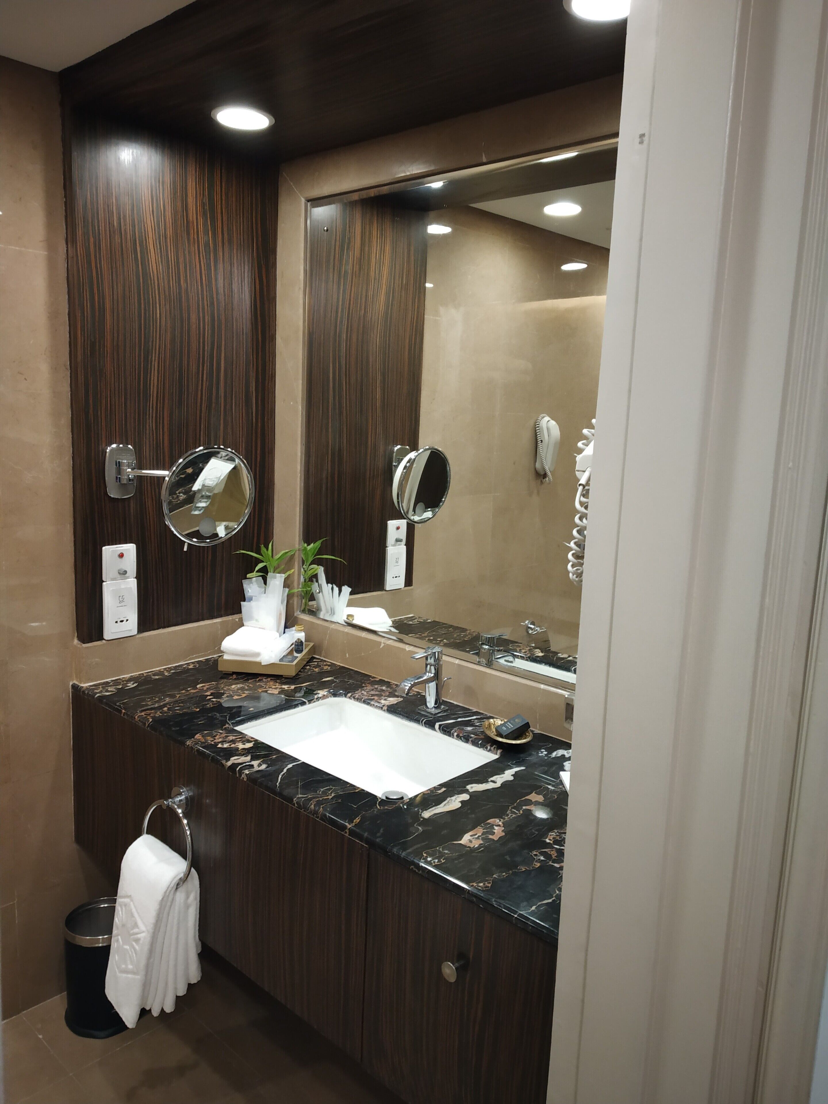 A modern bathroom with a dark wood vanity, a white sink, and a large mirror.