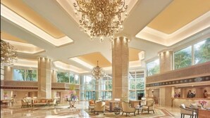 A spacious lobby with high ceilings, large windows, and a grand chandelier.