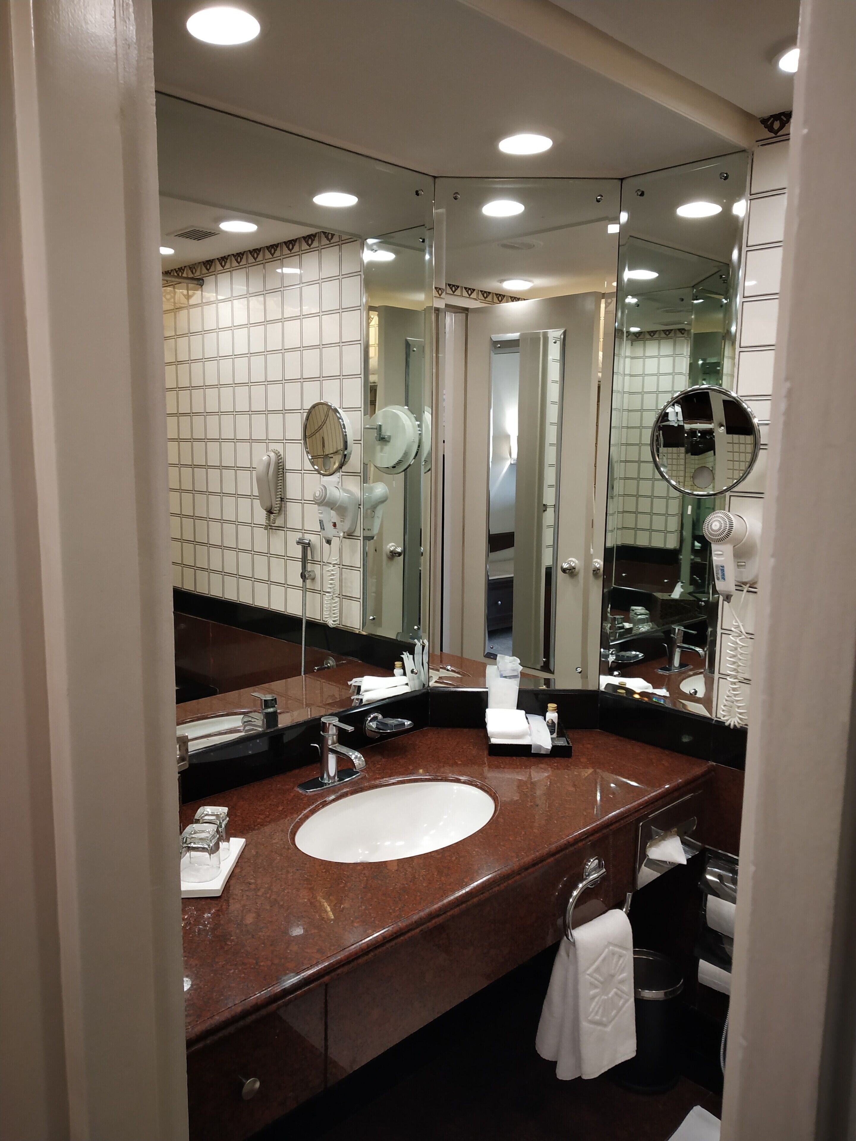 A modern bathroom with a large mirror, a sink, and a hairdryer.