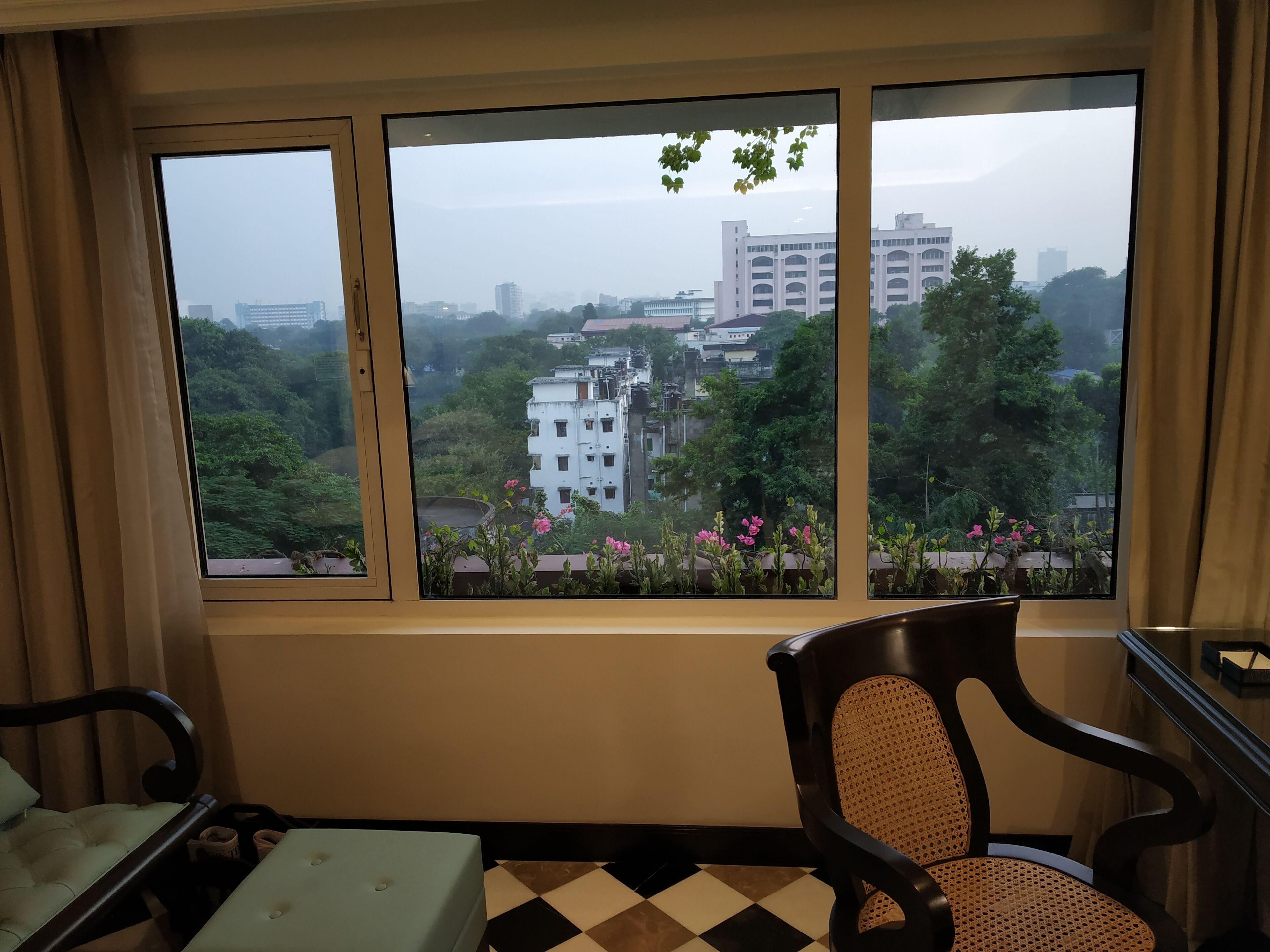 A room with a large window overlooking a cityscape, a chair, and a small table.