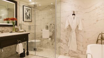 A modern bathroom with a glass-enclosed shower, a marble sink, and a white bathtub.