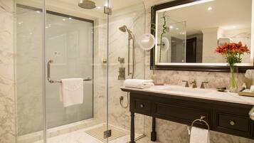A modern bathroom with a glass-enclosed shower, a marble vanity, and a large mirror.