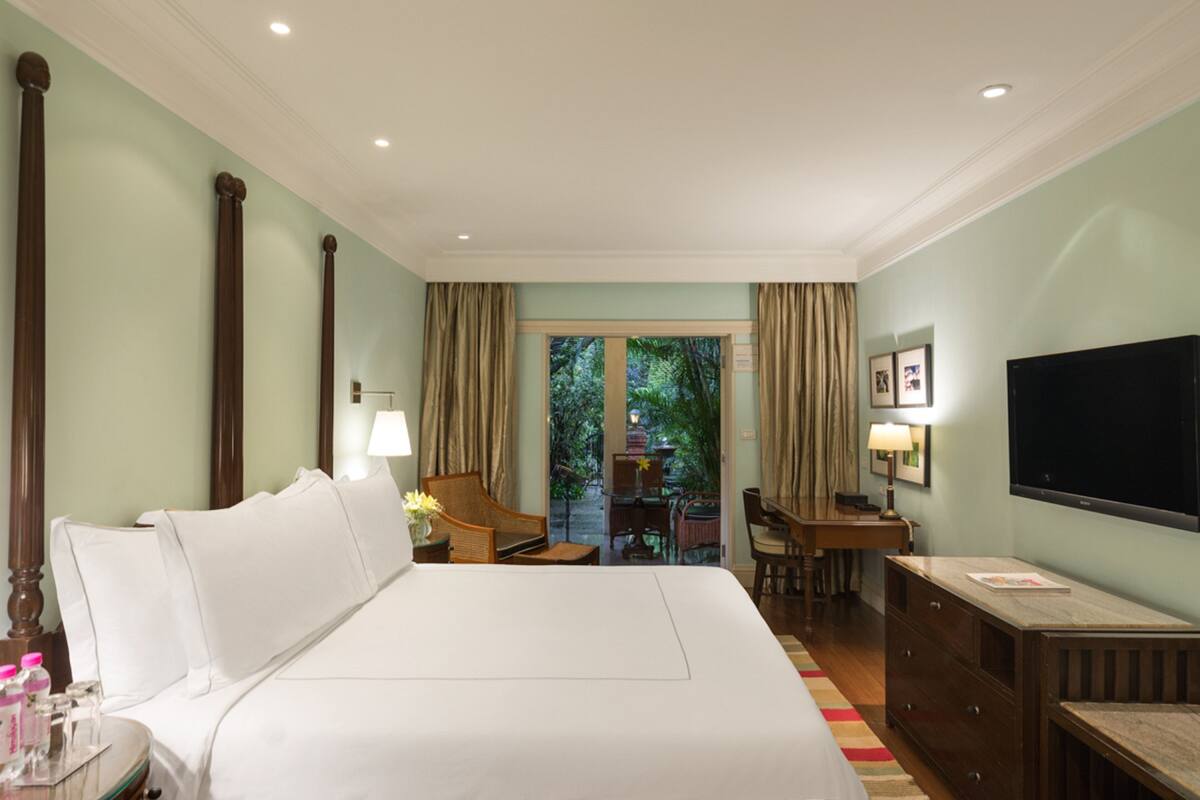 A hotel room with a large bed, a desk, a chair, a television, and a view of the outdoors.