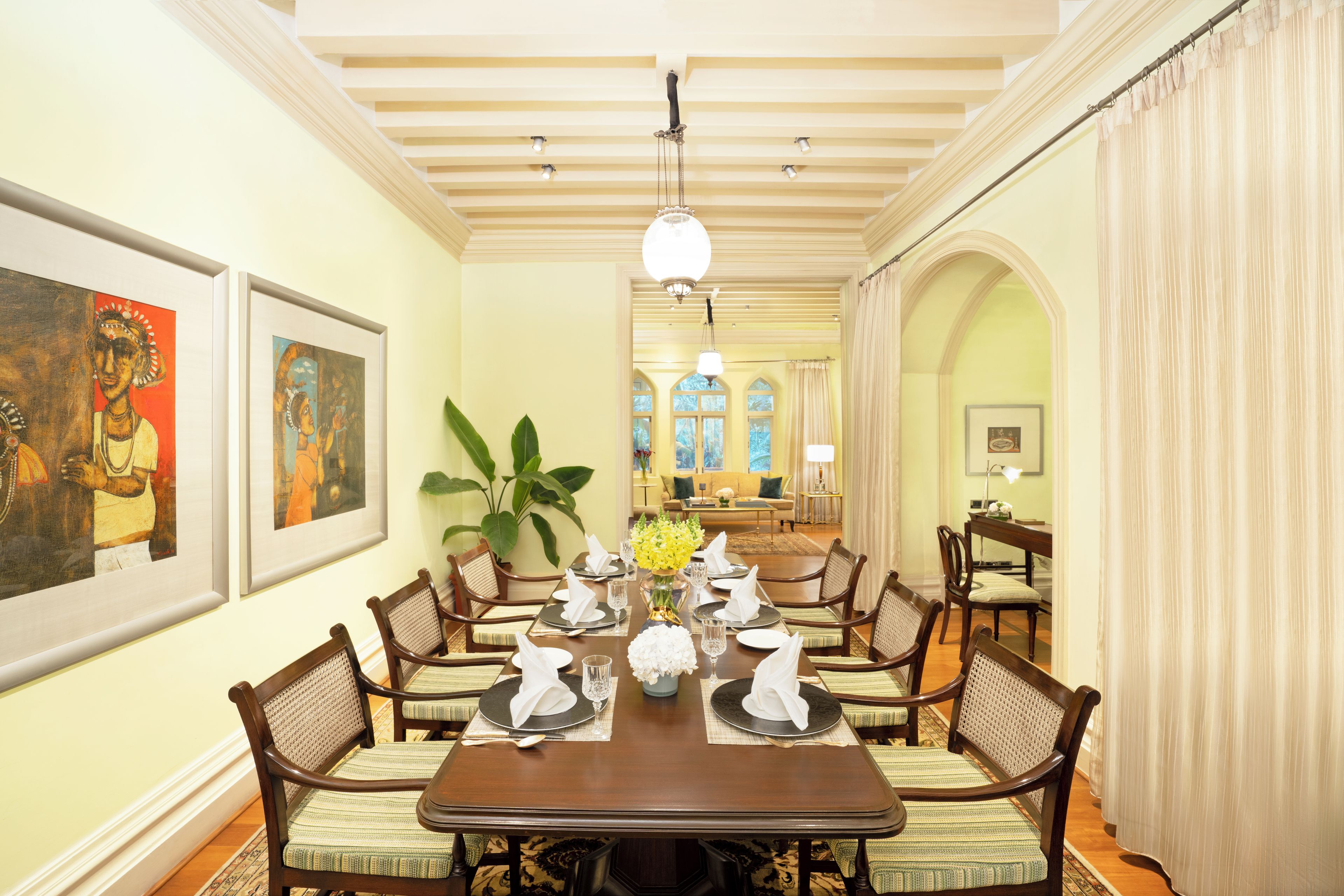 A dining room with a long table set for six, flanked by chairs with woven backs.