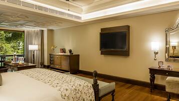 Habitación de hotel con una cama grande, un tocador, un espejo y un televisor en la pared.