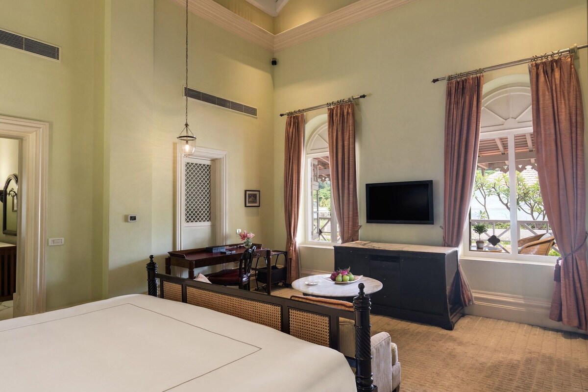 A hotel room with a bed, a desk, a television, and a window with curtains.