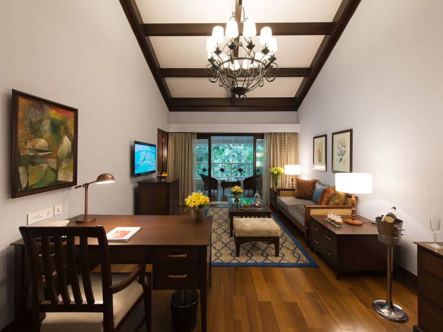 A modern living room with a wooden floor, a dining area with a table and chairs, a sofa, a coffee table, and a chandelier.