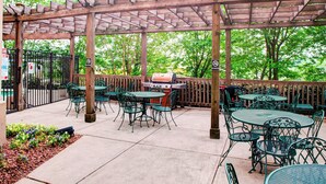 An outdoor patio with tables and chairs, a grill, and a wooden pergola. - TownePlace Suites by Marriott Atlanta Buckhead (Atlanta)
