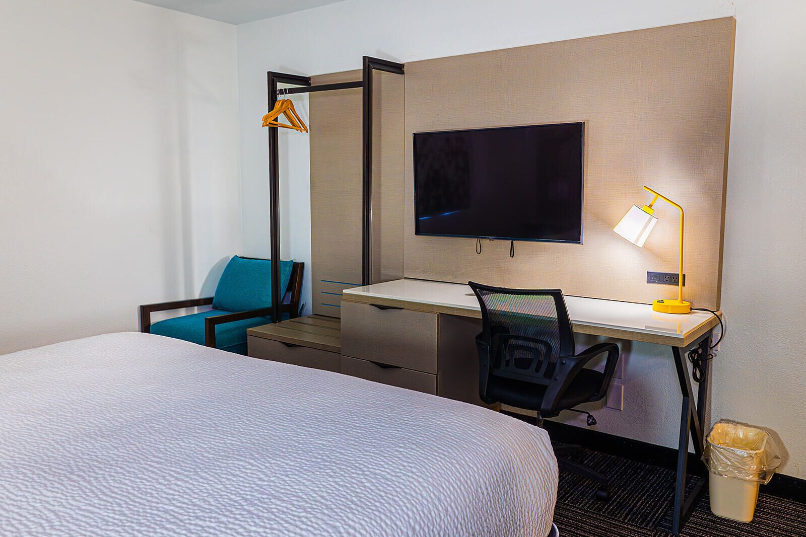 Une chambre d’hôtel comprenant un lit, un bureau avec une chaise, une télévision et une lampe.