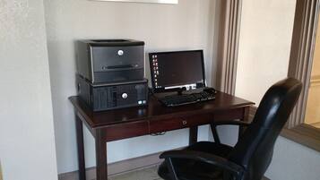 Un escritorio de madera con una computadora de escritorio, una impresora y una silla de oficina negra.