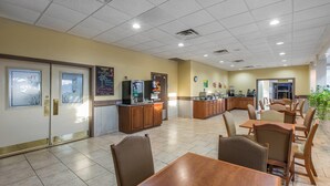 A restaurant with wooden tables and chairs, a counter with a cash register, and a clock on the wall. - Quality Inn & Suites Conference Center (Thomasville)