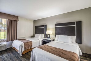 Two single beds with headboards and bedside tables, a window with curtains, and air conditioning unit.