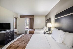 A hotel room with two beds, a television, a desk with a lamp, and a wardrobe. - Quality Inn & Suites Conference Center (Thomasville)
