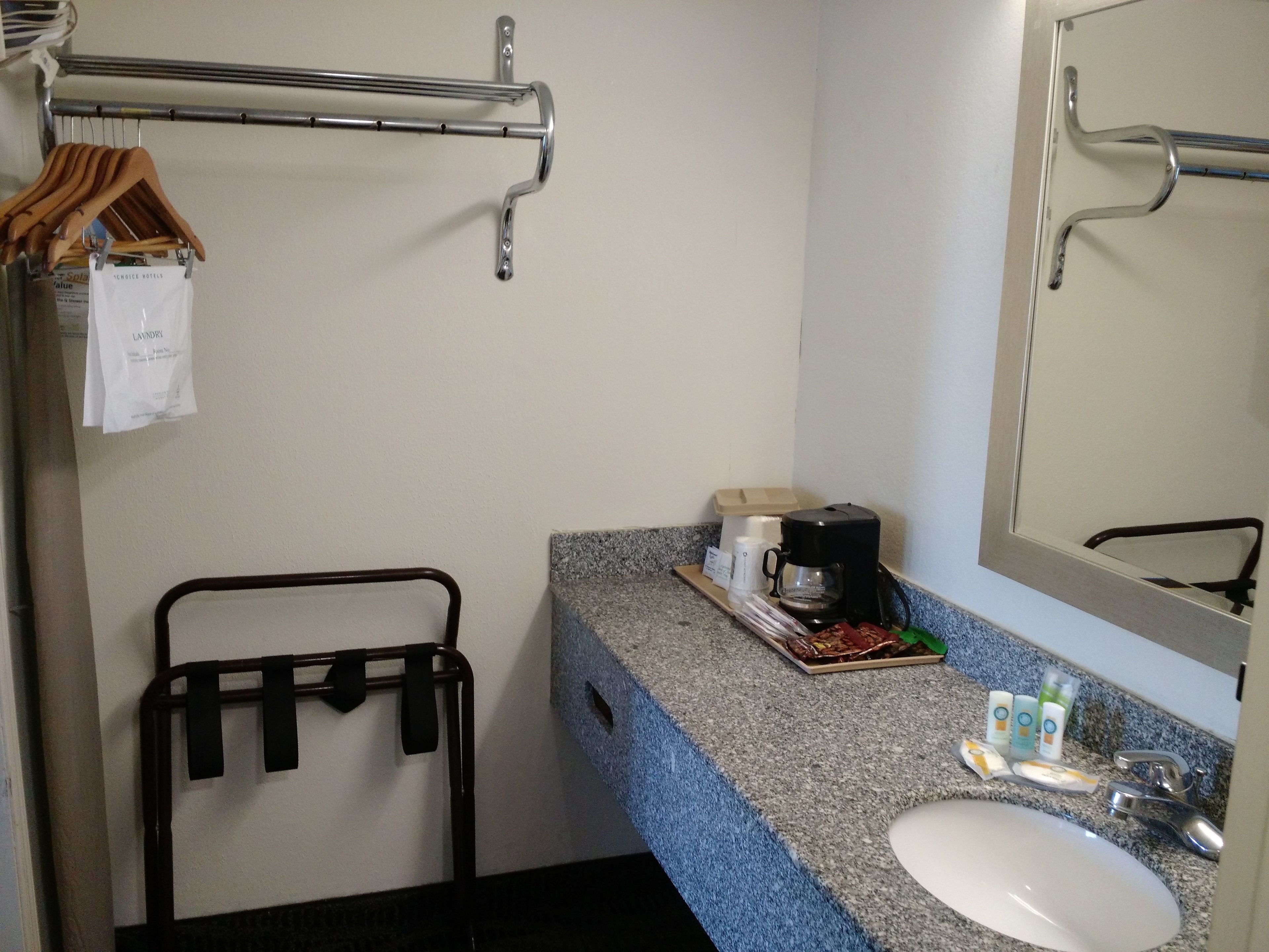 A bathroom with a sink, mirror, towel rack, and a coffee maker on the counter.