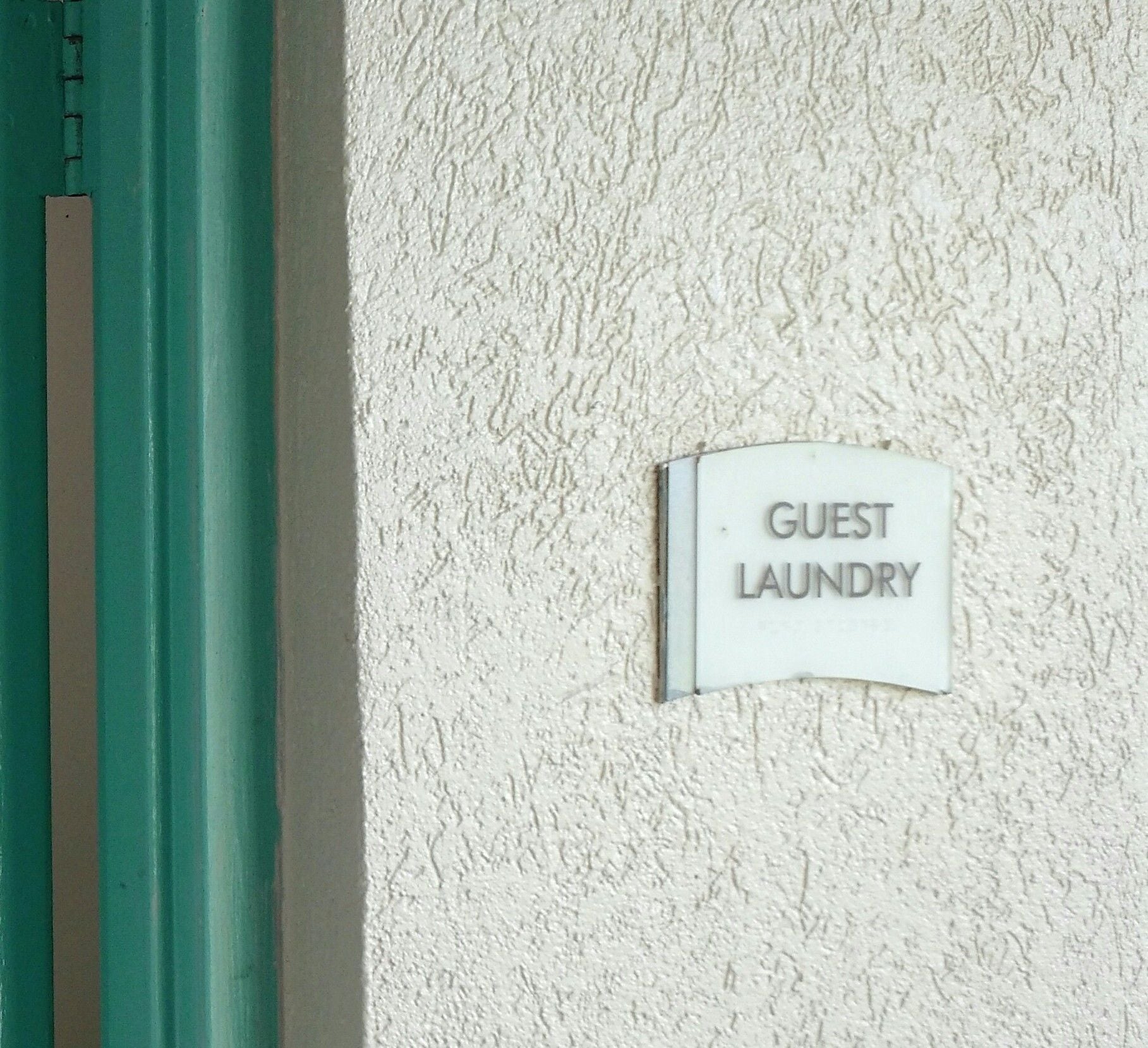 A sign on a textured wall that reads "GUEST LAUNDRY".