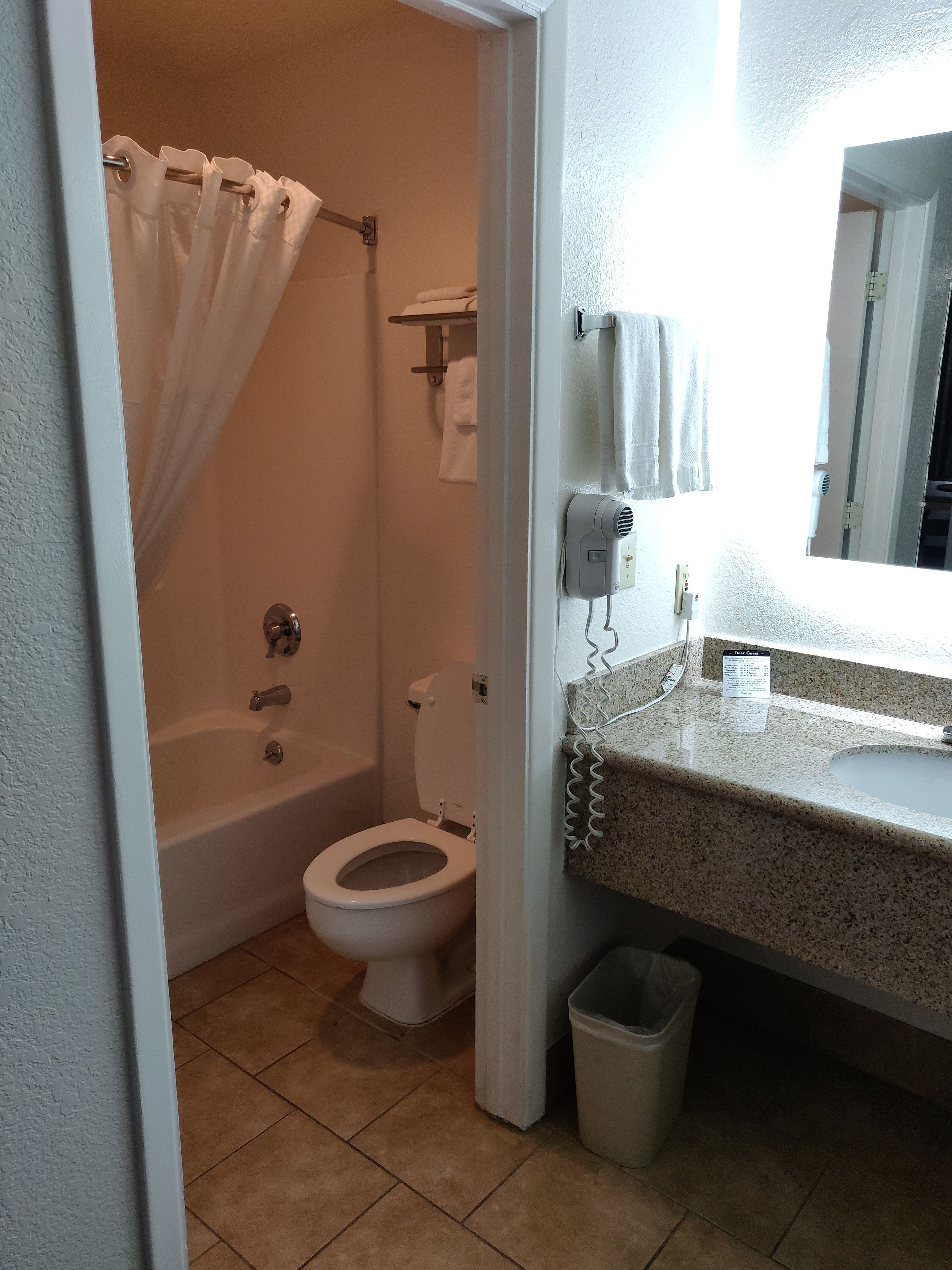 A bathroom with a bathtub, toilet, and a sink with a granite countertop.