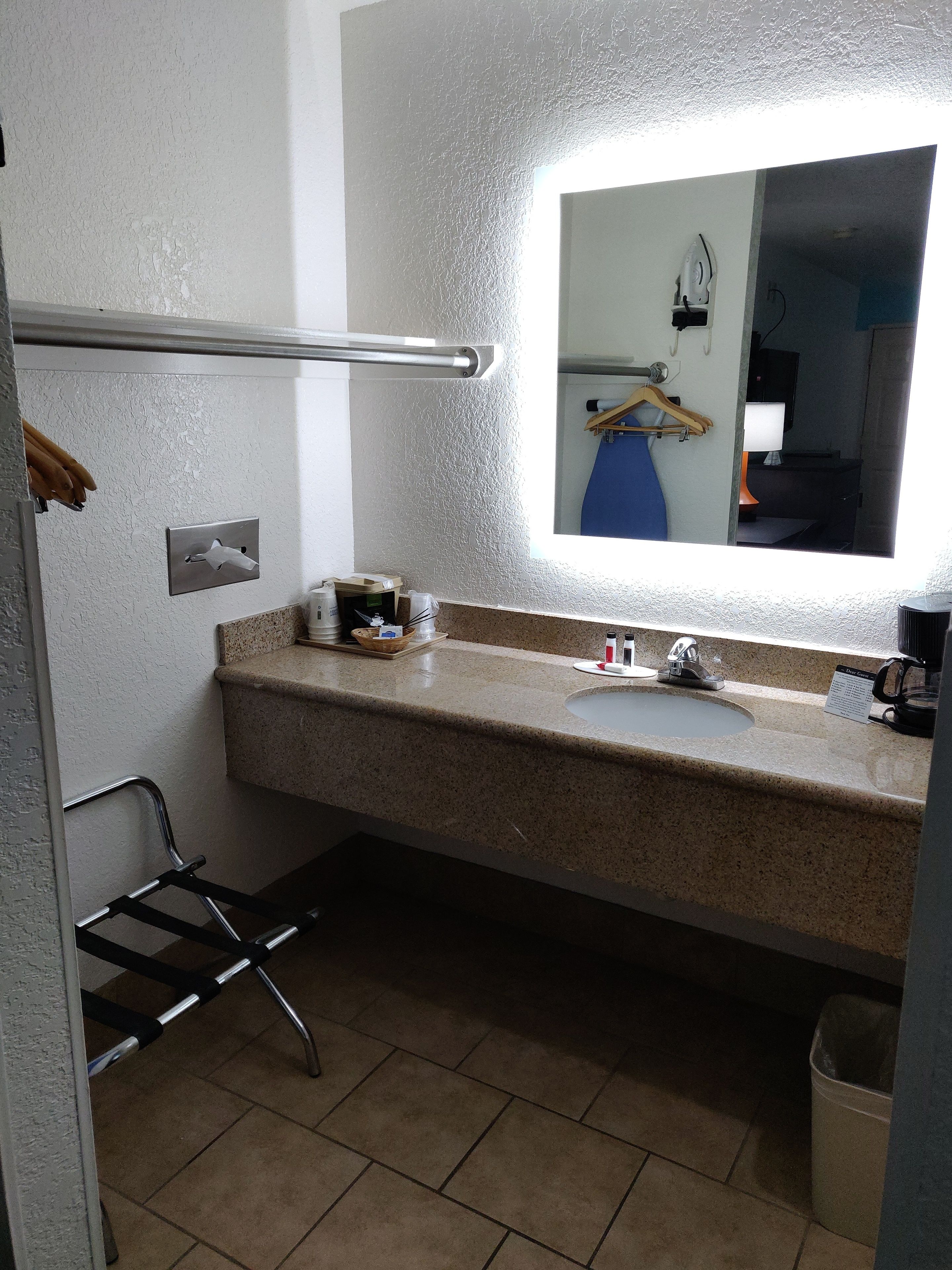 Ein Badezimmer mit Granitablage, Waschbecken, Spiegel und Handtuchhalter.