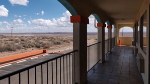A covered balcony with a view of a desert landscape.