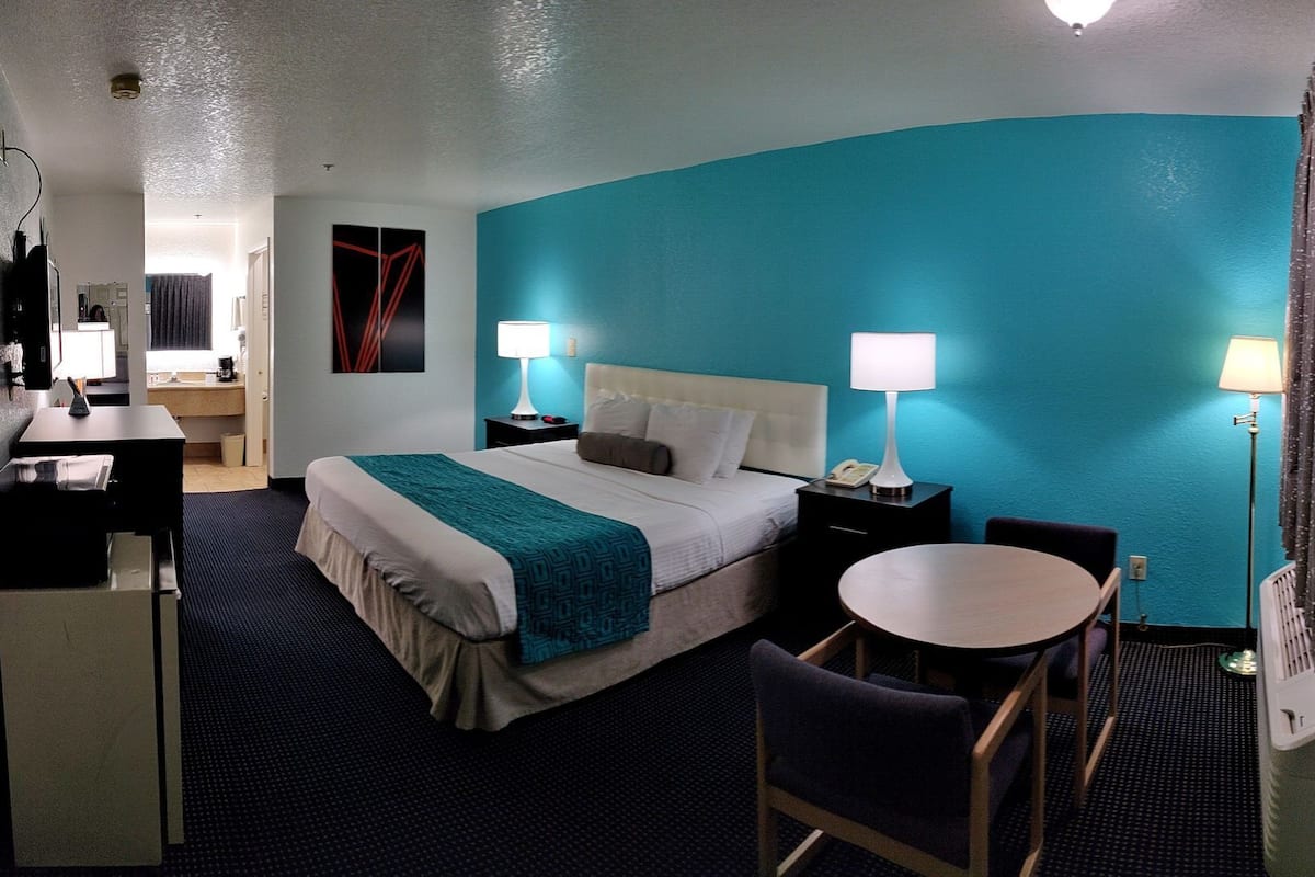 A hotel room with a bed, bedside tables, a desk, and a chair.
