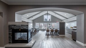 Une cuisine spacieuse dotée d’un îlot central, d’un coin repas avec des chaises et d’une cheminée.