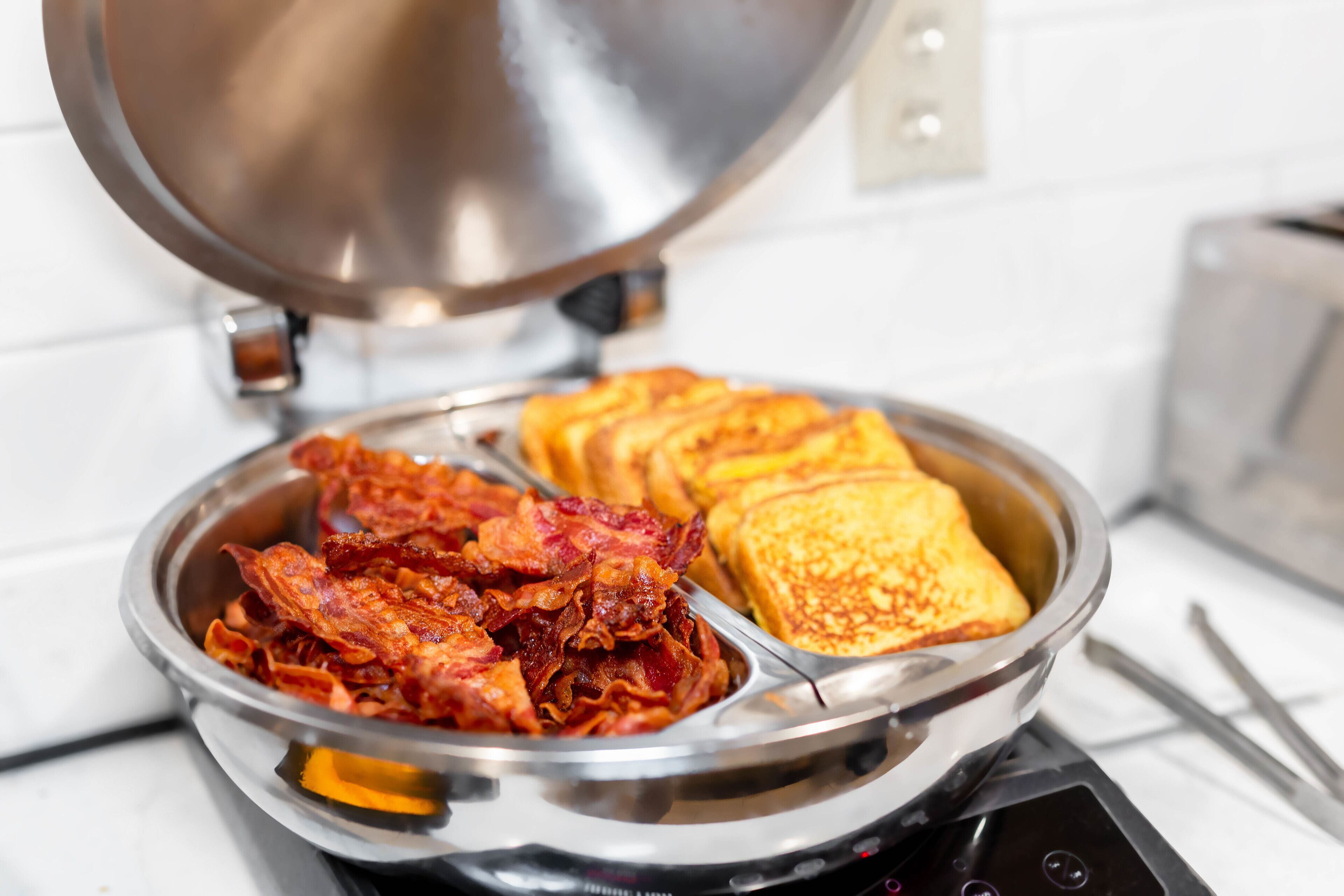A breakfast plate with bacon and toast on a portable stove.
