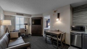 Une chambre d’hôtel équipée d’un canapé, d’un bureau, d’une télévision, d’un four à micro-ondes et d’une petite kitchenette.