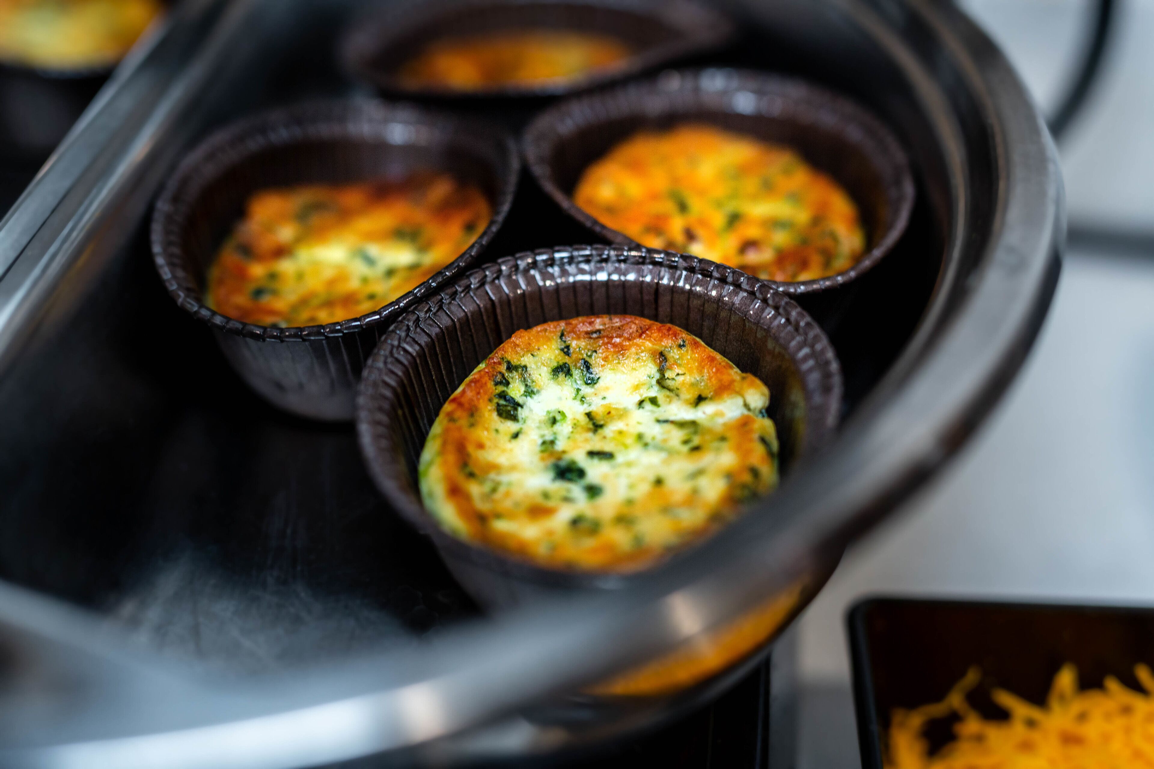 A tray with four muffin-like baked goods in individual foil containers.