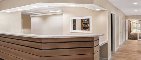 A reception area with a wooden counter, a small mirror, and a shelf with items.