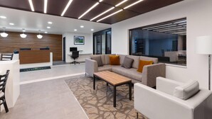 A modern office space with a reception desk, sofas, a coffee table, and a patterned rug. - Wingate by Wyndham Augusta I-20 (Augusta)