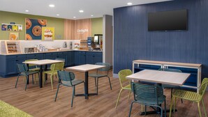 Une cuisine moderne avec des meubles en bois, un îlot central et un coin repas agrémenté de chaises vertes et d’une table.