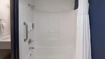 A modern bathroom with a glass shower enclosure, white fixtures, and a dark blue accent wall.