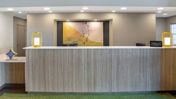 A reception desk with a modern design, a large abstract painting above it, and two wall-mounted lamps on either side.