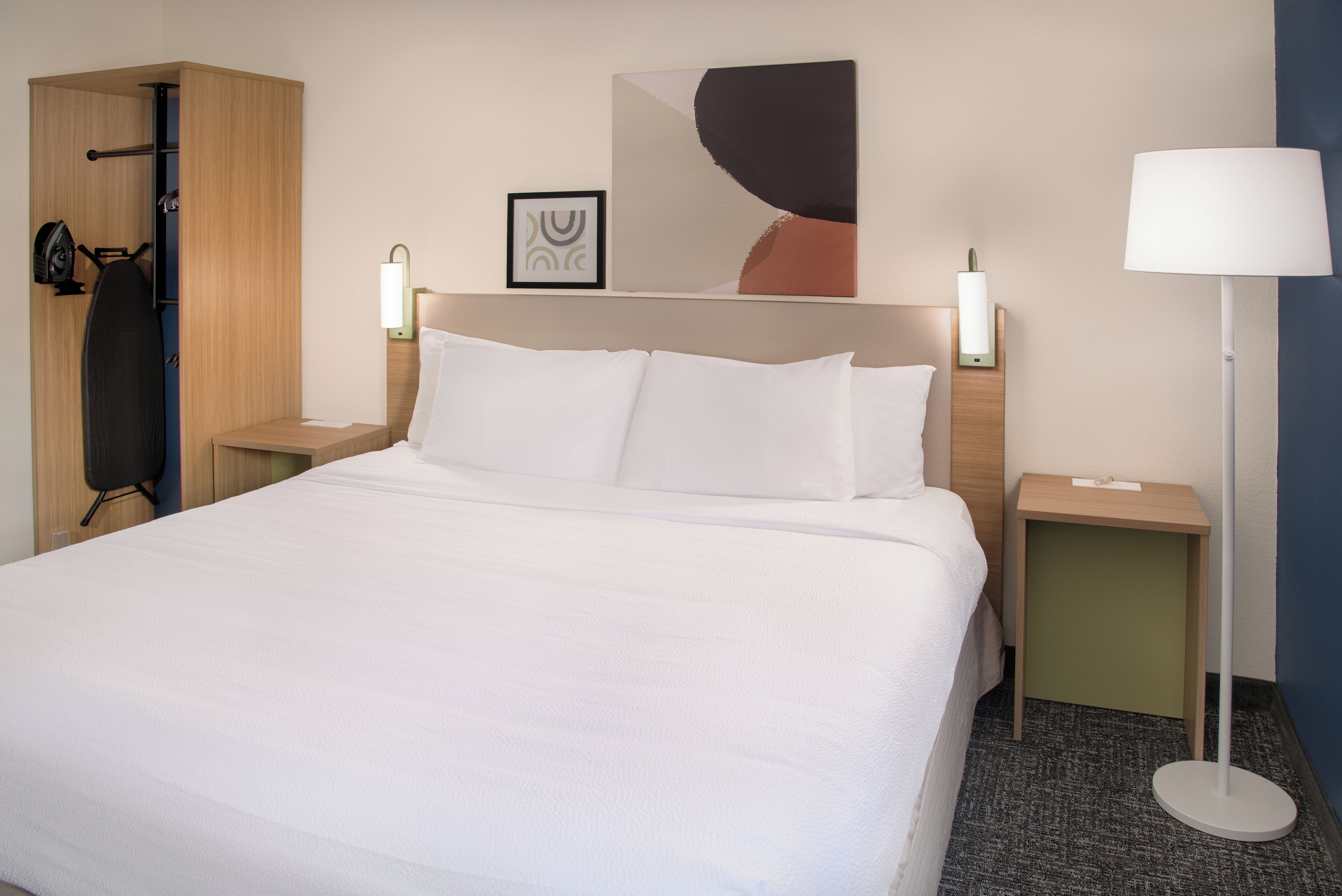 A neatly made bed with white linens, a wooden headboard, and two bedside tables with lamps.