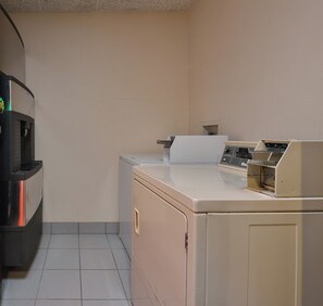 A compact kitchen with a refrigerator, a washing machine, and a microwave.