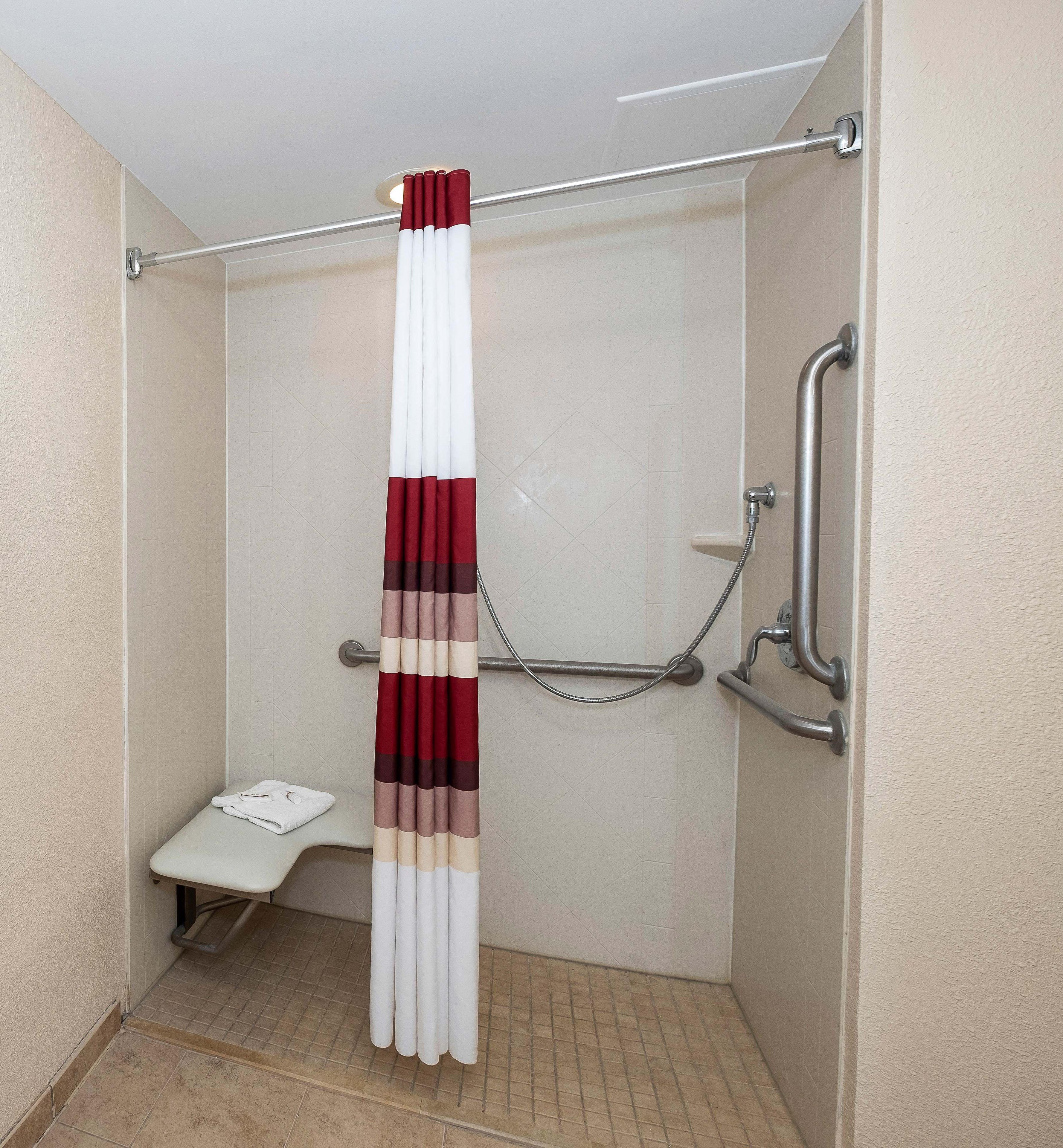 A shower area with a grab bar, a towel rack, and a small bench.