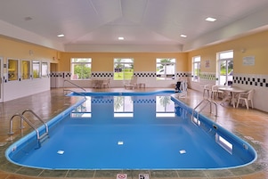 Una piscina con indicador de profundidad de 1.5 metros, rodeada de un suelo de baldosas, con ventanas que ofrecen vistas al exterior.